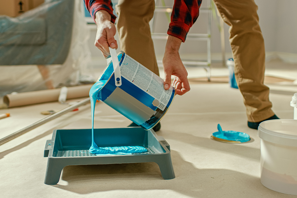 Professional painter pouring blue paint to paint home with